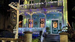 A two-story house with a porch decorated with string lights and a sign that reads "Prince & Princess Inn." - Peace & Plenty Inn Bed & Breakfast (St. Augustine)