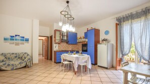 A compact kitchen with blue cabinets, a dining table set for four, and a sofa in the living area. - 3 bedroom pet friendly home in Marina di Modica (Marina di Modica)