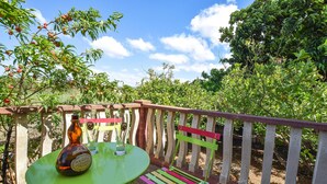A green table with a bottle and glasses, a colorful bench, and a view of trees and sky. - 3 bedroom pet friendly home in Marina di Modica (Marina di Modica)