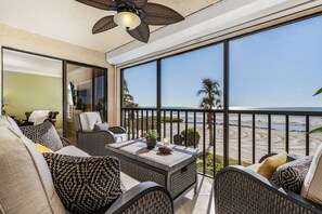 A balcony with wicker furniture, a ceiling fan, and a view of the beach. - Not available due to hurricane Ian damage (Fort Myers Beach)