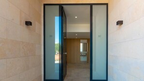 A modern entrance with glass doors, a tiled floor, and a view into a room with a sink. - Can Navarro by Interhome (Inca)