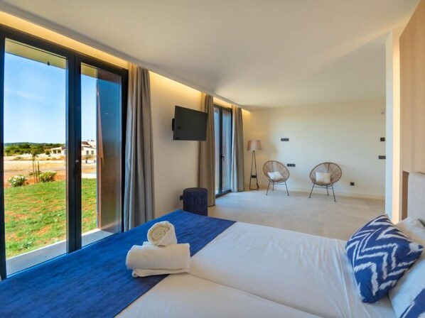A modern hotel room with a large bed, a TV mounted on the wall, and a view of the outdoors.