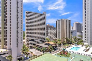 Experience the urban lifestyle in this high-rise building with a rooftop pool surrounded by palm trees and a deck area.