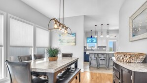 Een moderne keuken met een centraal eiland, houten vloer en hangende lampen.