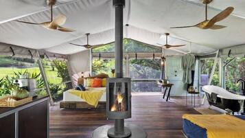 Alojamiento con tiendas de campaña, chimenea central, ventiladores de techo y vistas al exterior.