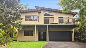 Une maison à deux étages avec un garage, un balcon et une grande fenêtre.
