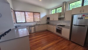 Une cuisine moderne avec un plancher en bois, des appareils électroménagers en acier inoxydable et de grandes fenêtres.