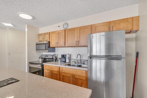 A modern kitchen with wooden cabinets, stainless steel appliances, and a granite countertop.