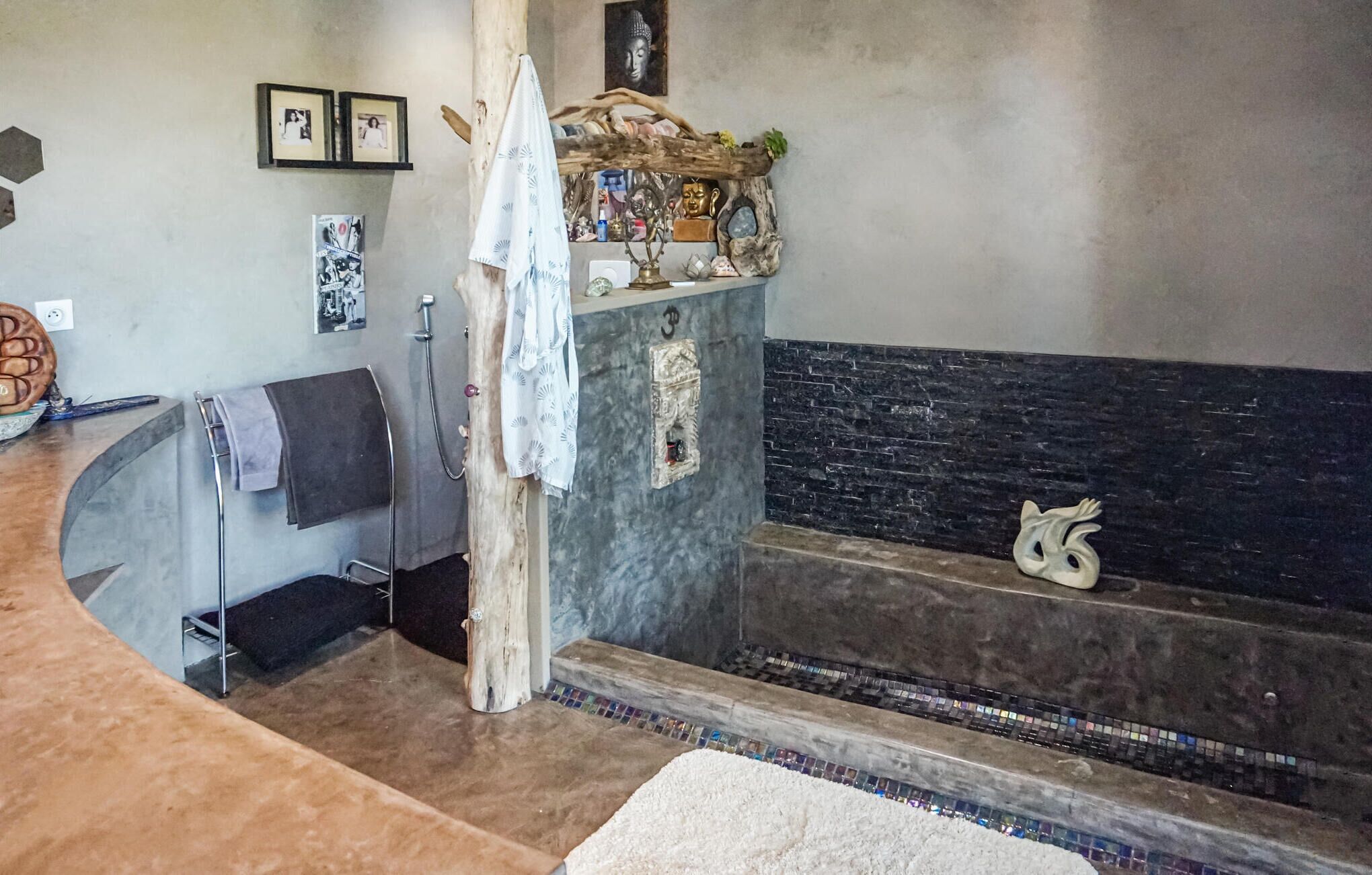 Un bagno con un mobile da bagno curvo, una doccia e una vasca da bagno rivestita di mosaici.
