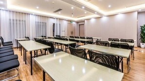 A conference room with multiple tables and chairs, a large window with curtains, and a potted plant.