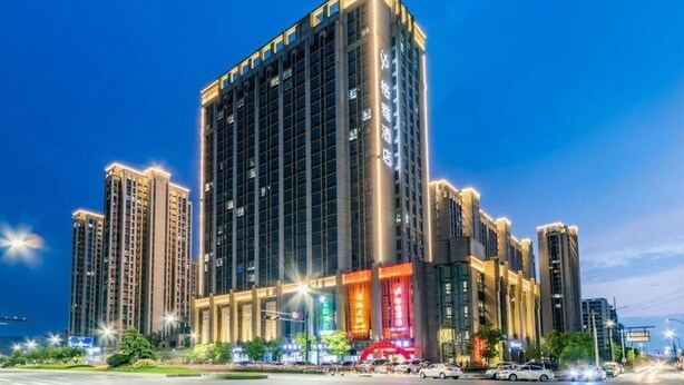 A high-rise hotel with multiple floors, large windows, and illuminated signage.