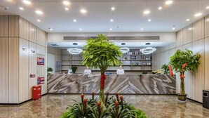 A modern reception area with marble flooring, a reception desk, and potted plants.