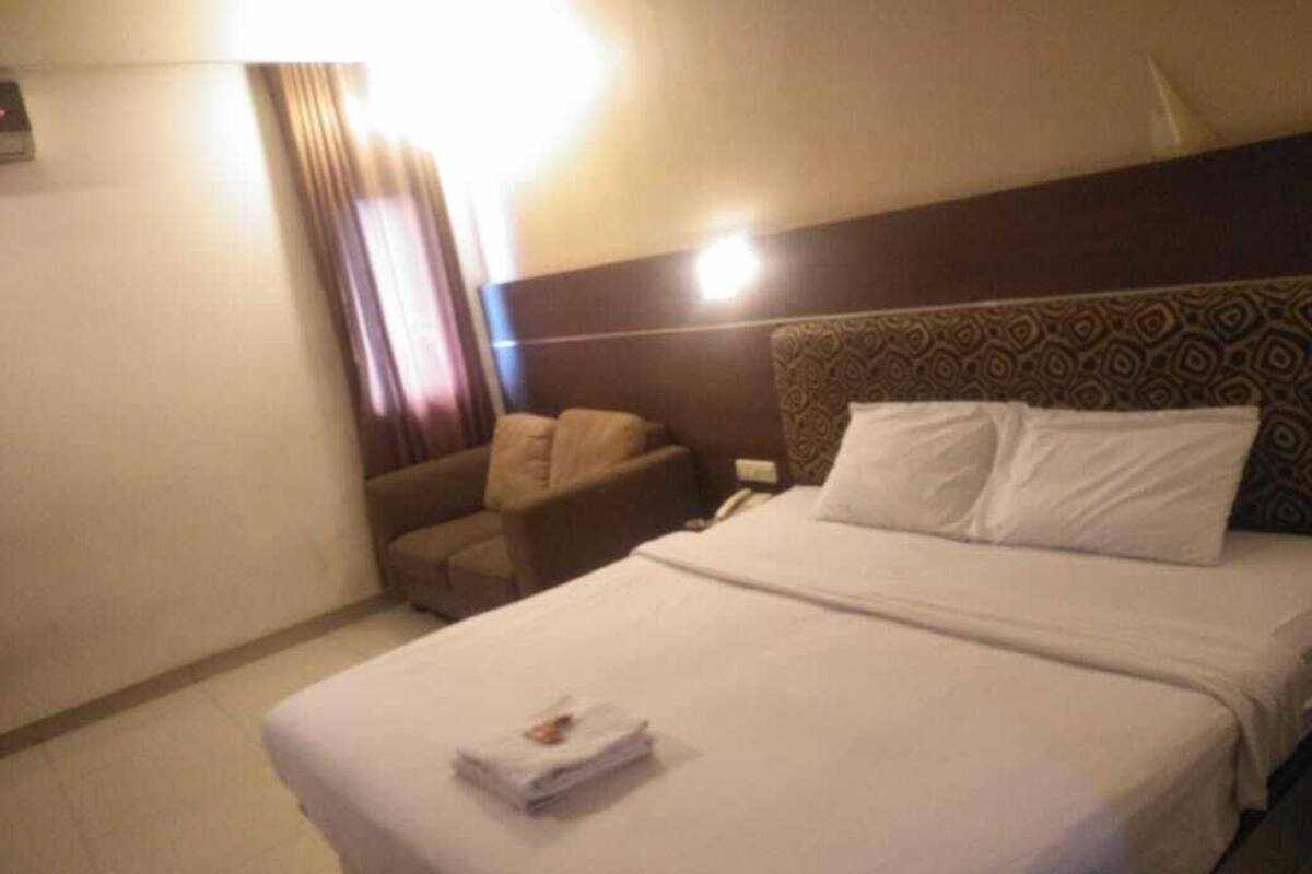 A hotel room with a bed, a chair, and a bedside table.