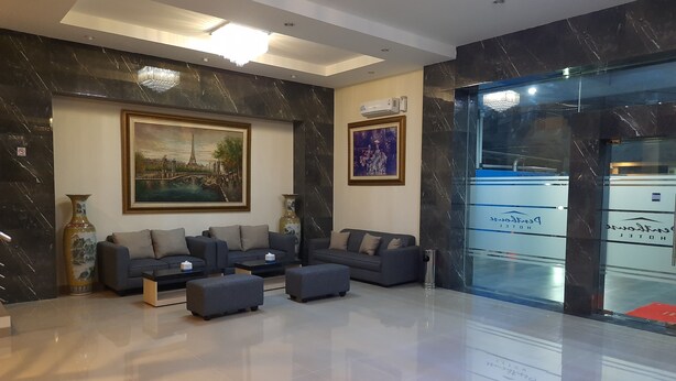 A modern lobby with a sofa set, a large painting, and a glass wall with hotel signage. - Ams Penthouse (Jakarta)