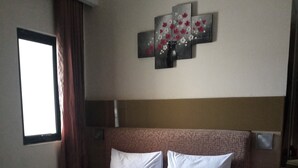 A hotel room with a large bed, a bedside table with a phone, and a wall-mounted artwork. - Ams Penthouse (Jakarta)