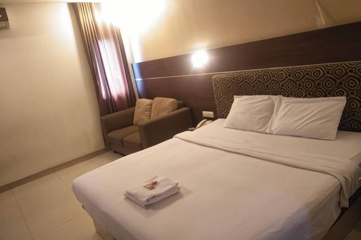 A hotel room with a bed, a chair, and a nightstand.