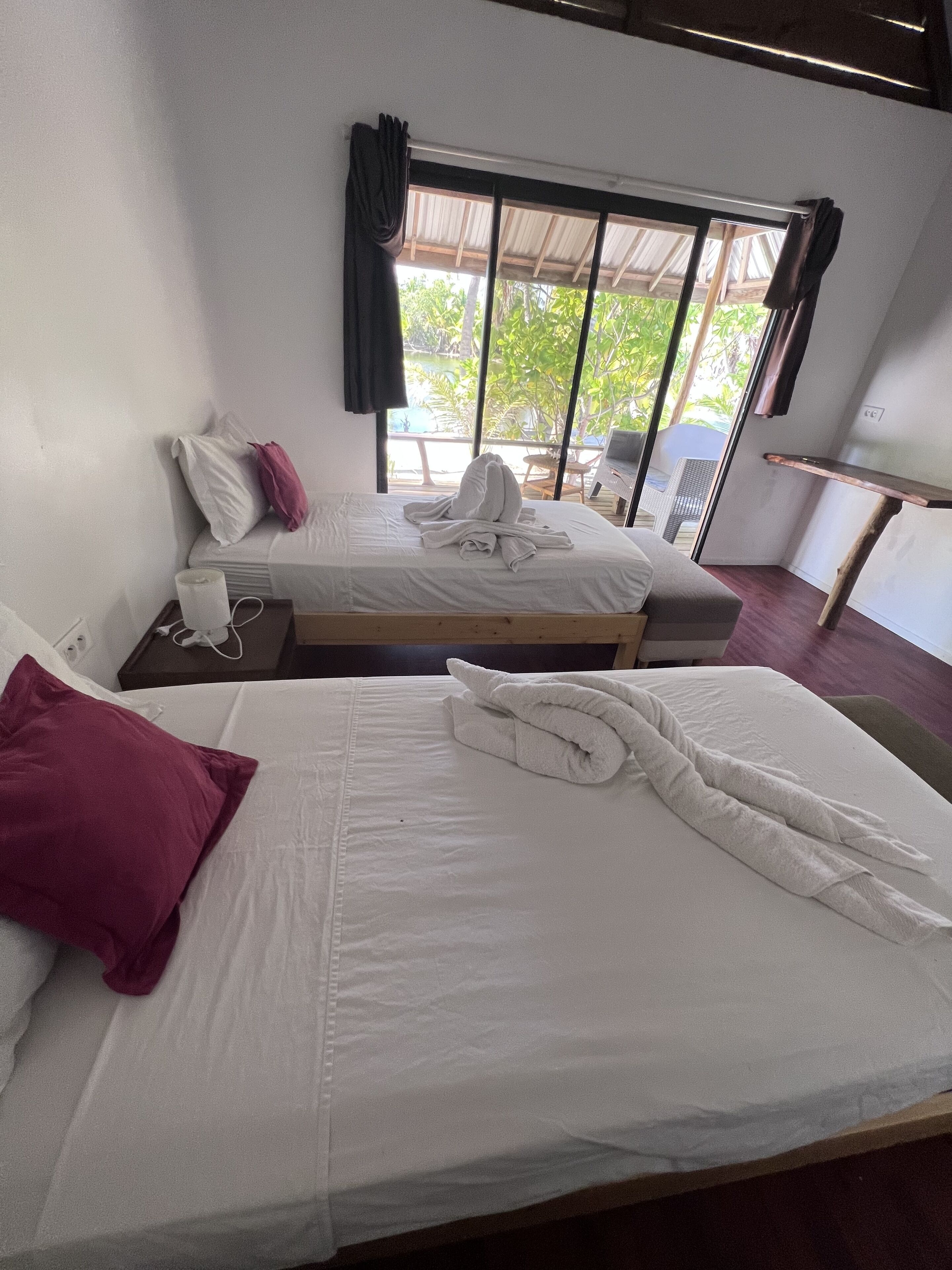 Quarto de hotel com duas camas, uma escrivaninha e janela com cortinas.