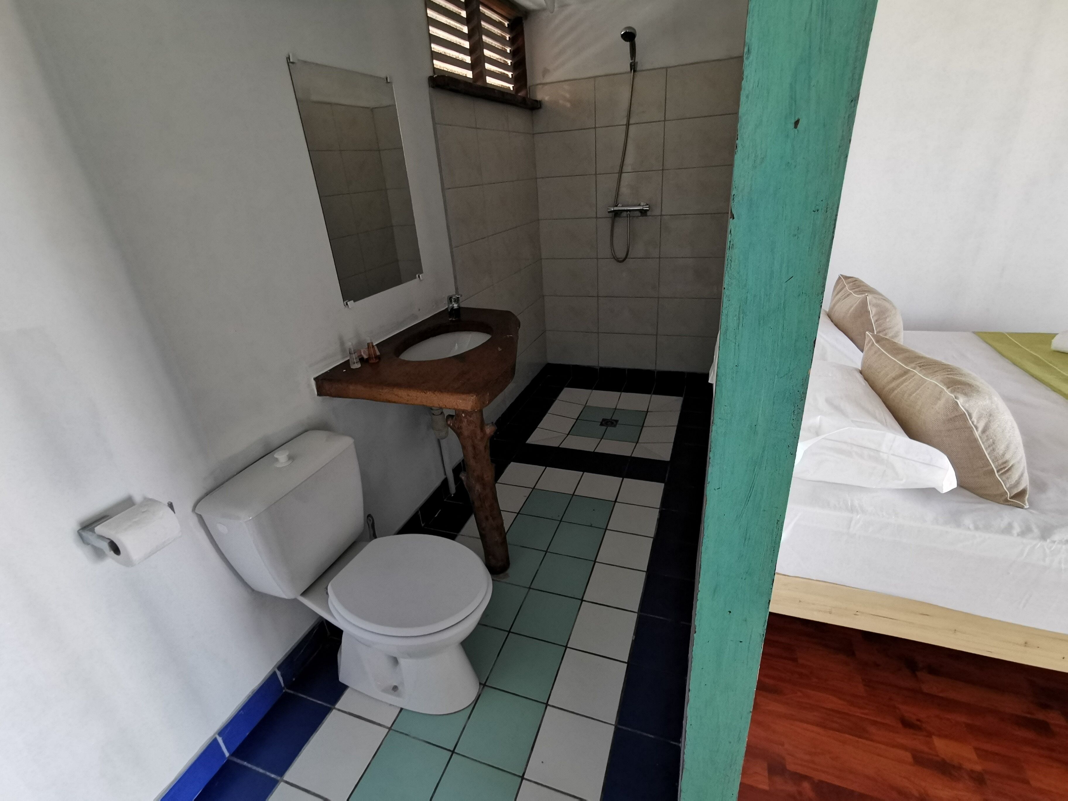 A small, compact bathroom with a toilet, sink, and shower.
