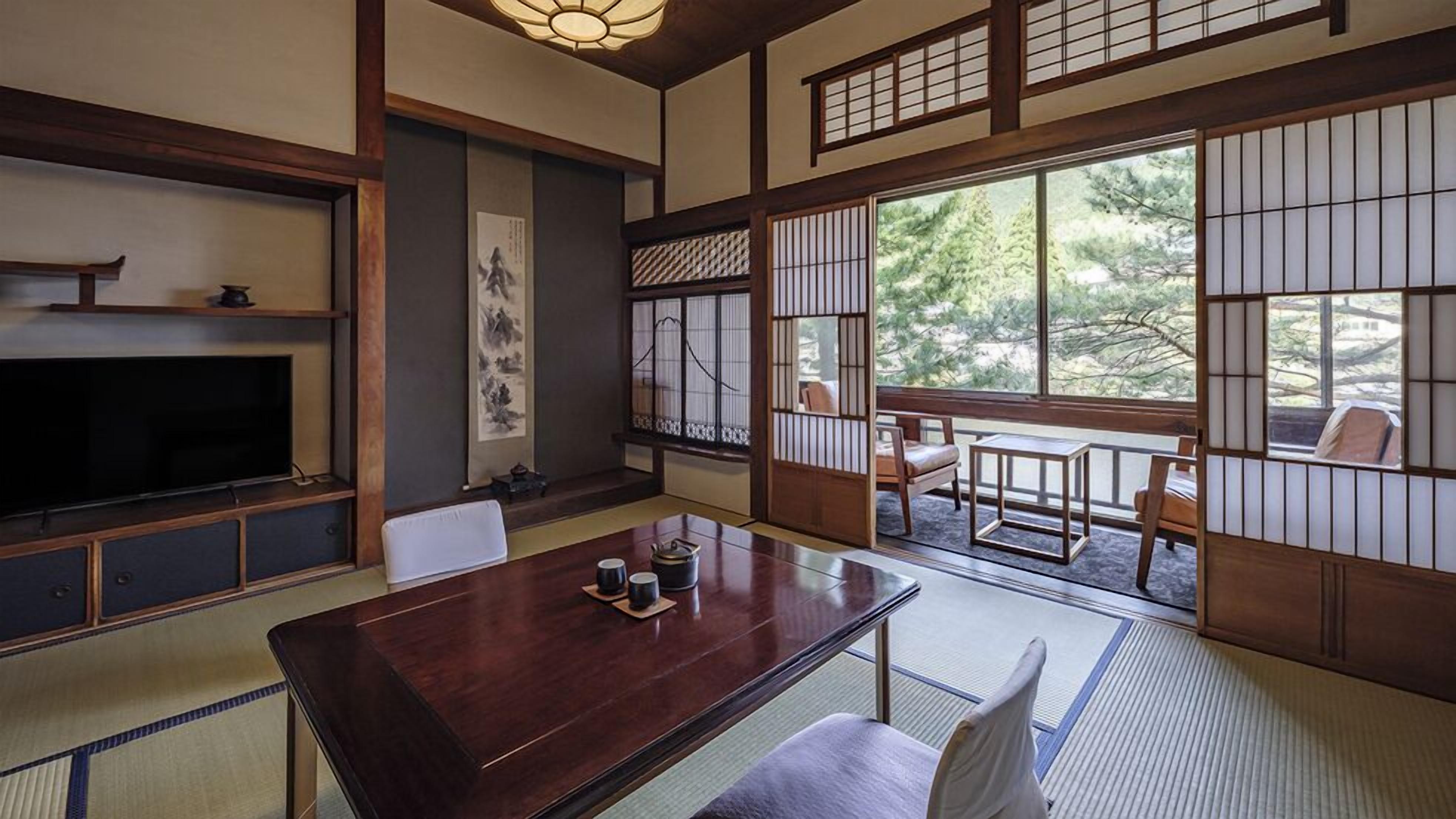 A traditional Japanese-style room with tatami flooring, a low table, a television, and sliding doors.