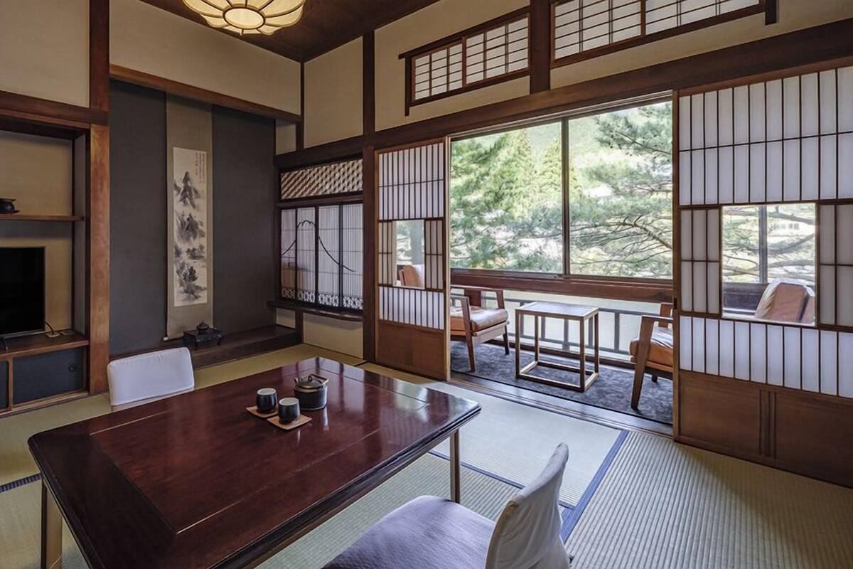 Une pièce de style japonais traditionnel, avec un sol recouvert de tatamis, une table basse, un téléviseur et des portes coulissantes.