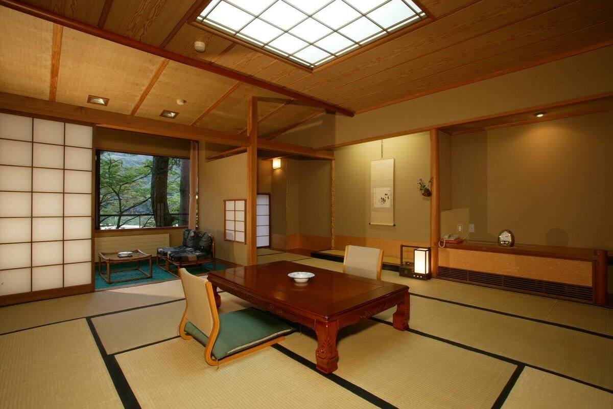 Une pièce de style japonais traditionnel, avec un sol recouvert de tatamis, une petite table en bois et une porte coulissante.