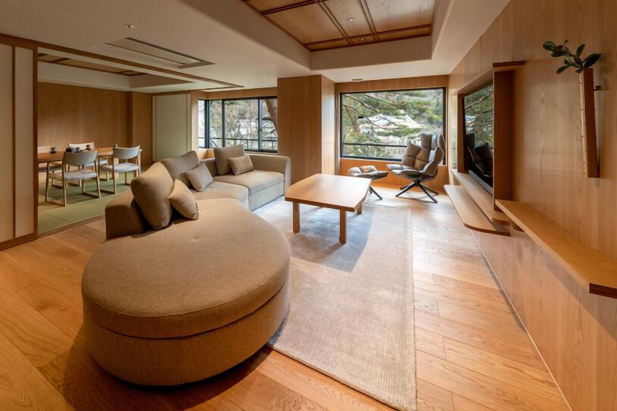Un salon moderne avec un pouf rond, un canapé, une table basse et un téléviseur.