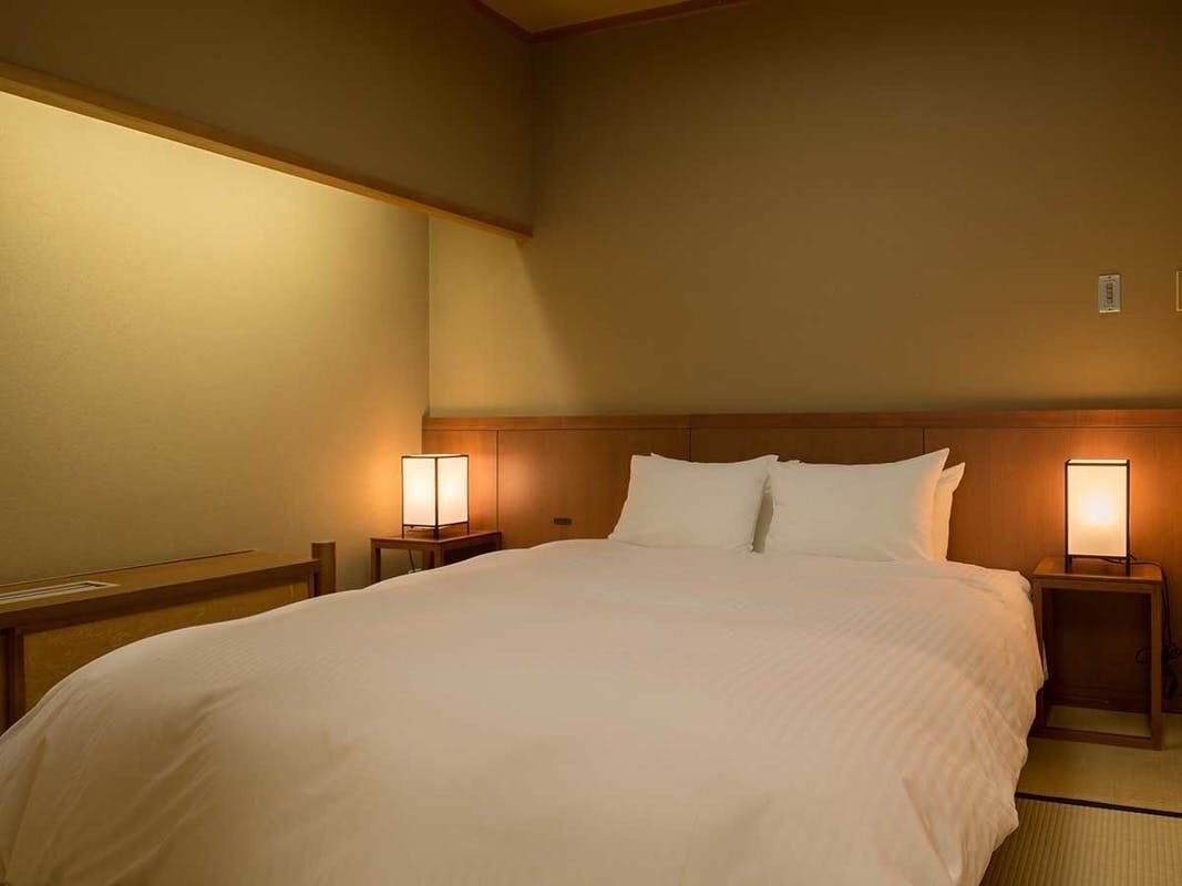 A hotel room with a large bed, two bedside tables with lamps, and a wooden headboard.