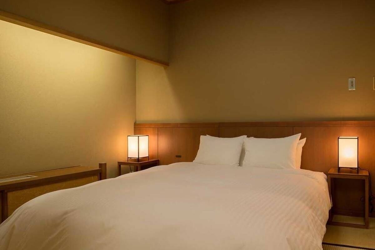 Une chambre d’hôtel avec un grand lit, deux tables de chevet avec des lampes et une tête de lit en bois.