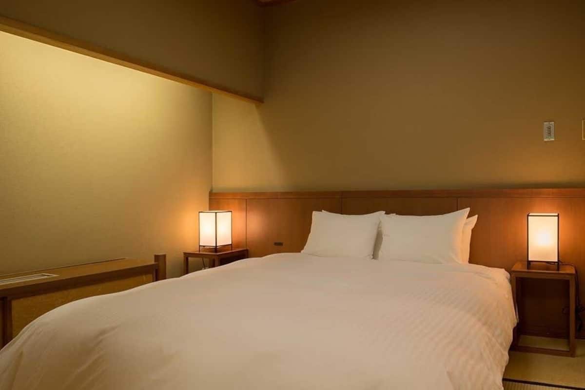 Una habitación de hotel con una cama grande, dos mesitas de noche con lámparas y un cabecero de madera.