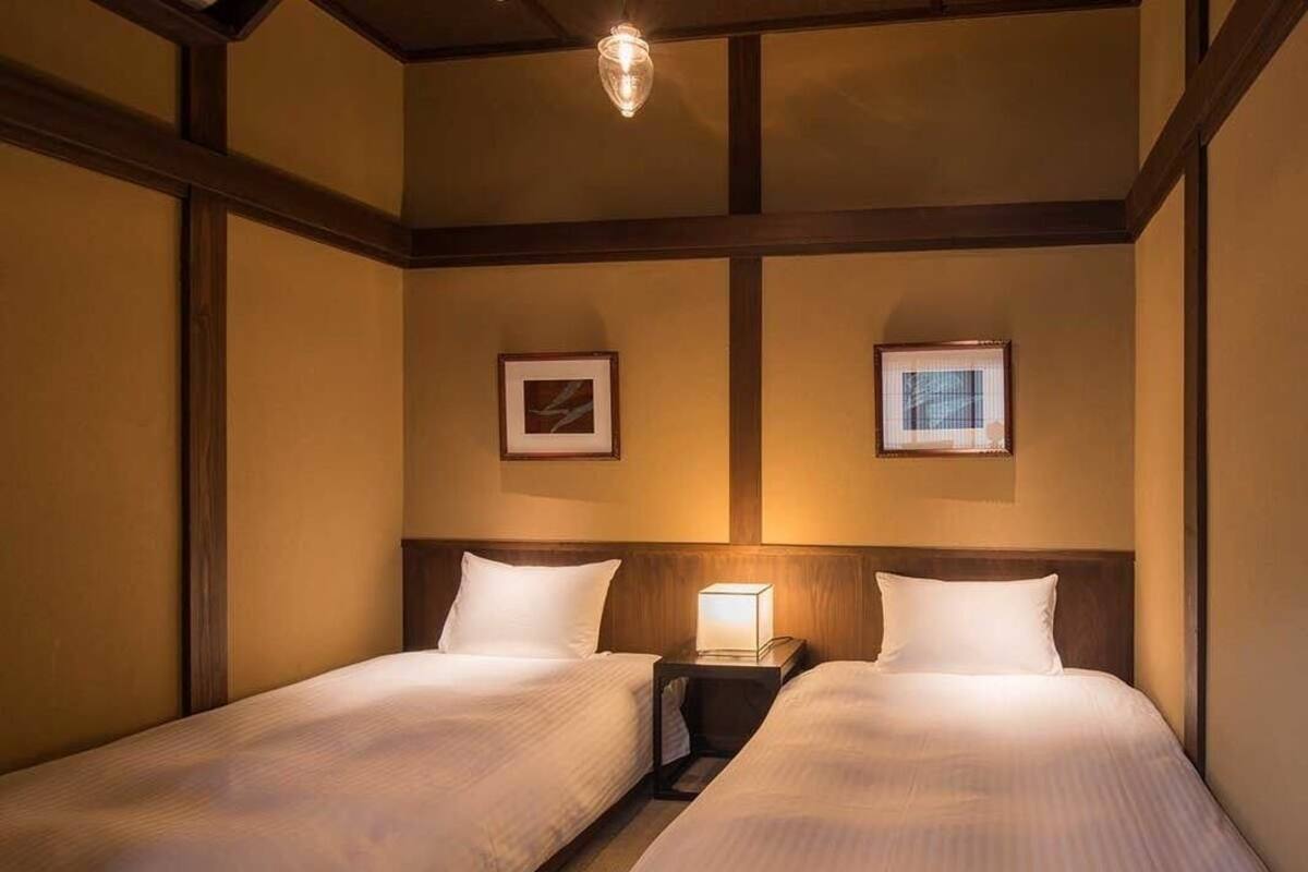 Une chambre d’hôtel avec deux lits, une table de chevet avec une lampe et des tableaux encadrés au mur.