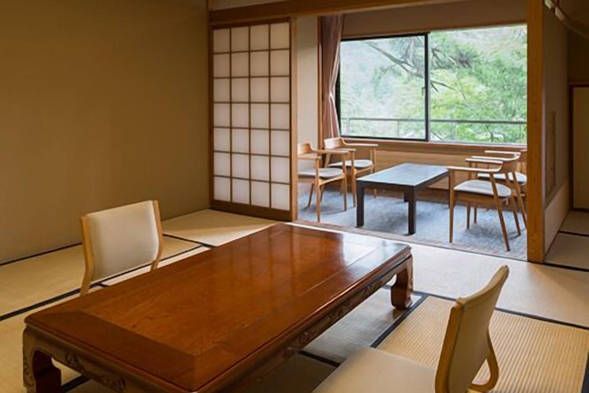 Une pièce de style japonais traditionnel, avec un sol recouvert de tatamis, une table en bois et de petites chaises en bois.
