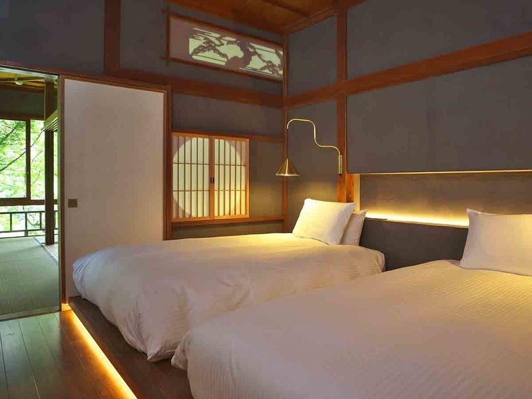 A room with two beds, a traditional Japanese-style window, and a modern lamp.