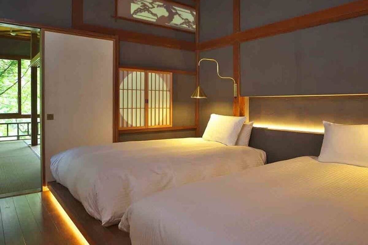 Une chambre avec deux lits, une fenêtre de style japonais traditionnel et une lampe moderne.