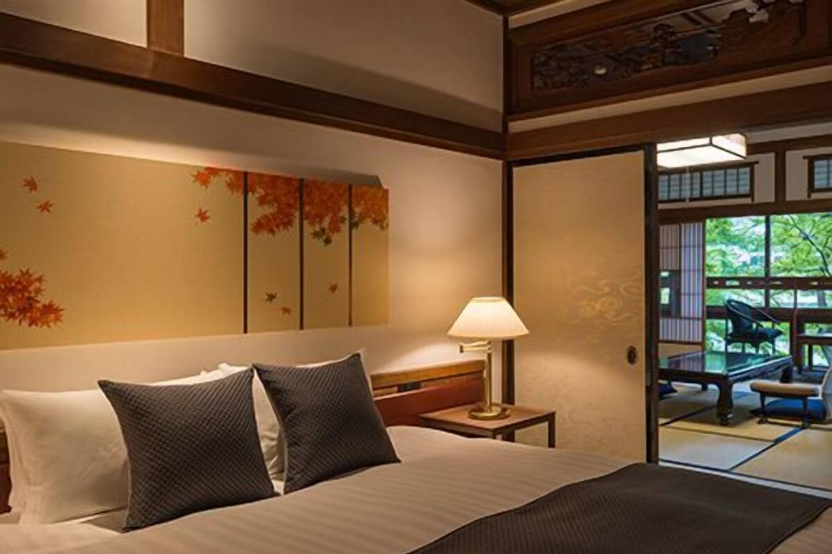 Une chambre d’hôtel avec un lit, des oreillers, une table de chevet avec une lampe et une vue sur l’extérieur grâce à une porte coulissante.