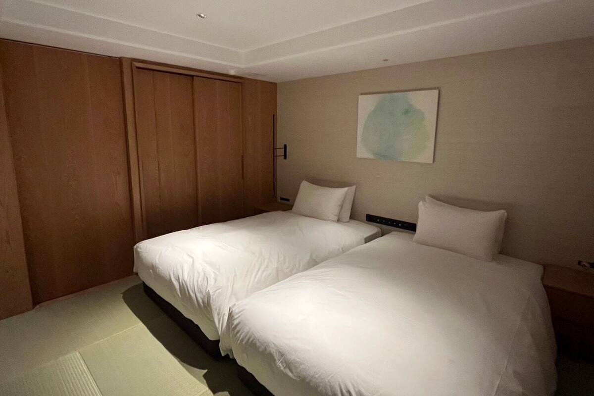 Une chambre d’hôtel avec deux lits, une armoire en bois et un tableau au mur.