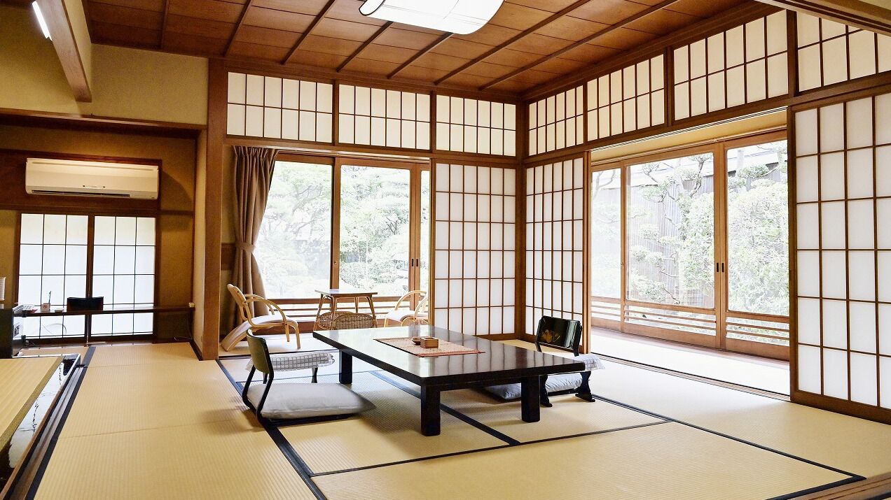 A traditional Japanese room with tatami flooring, sliding shoji doors, a low table, and a sofa.