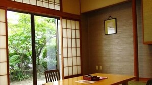 Quarto japonês tradicional com tatames, uma porta deslizante e uma mesa baixa com almofadas.