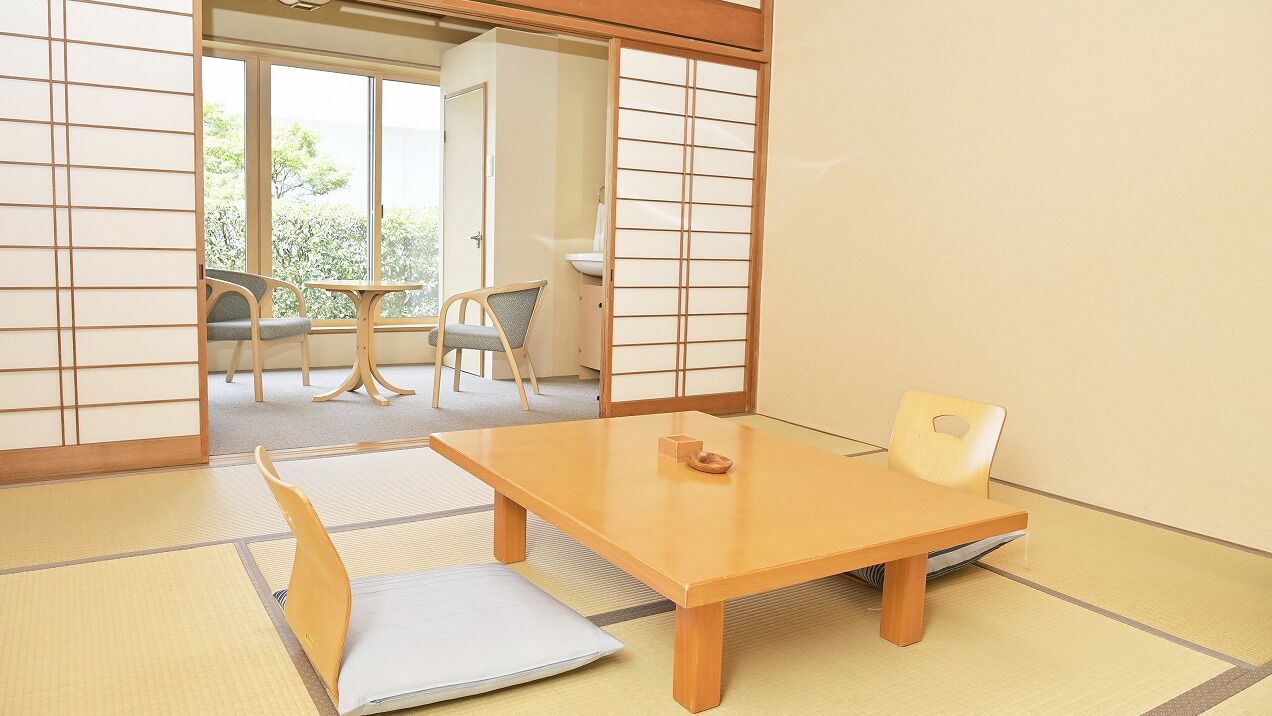 A traditional Japanese room with tatami flooring, a low table, and sliding doors.