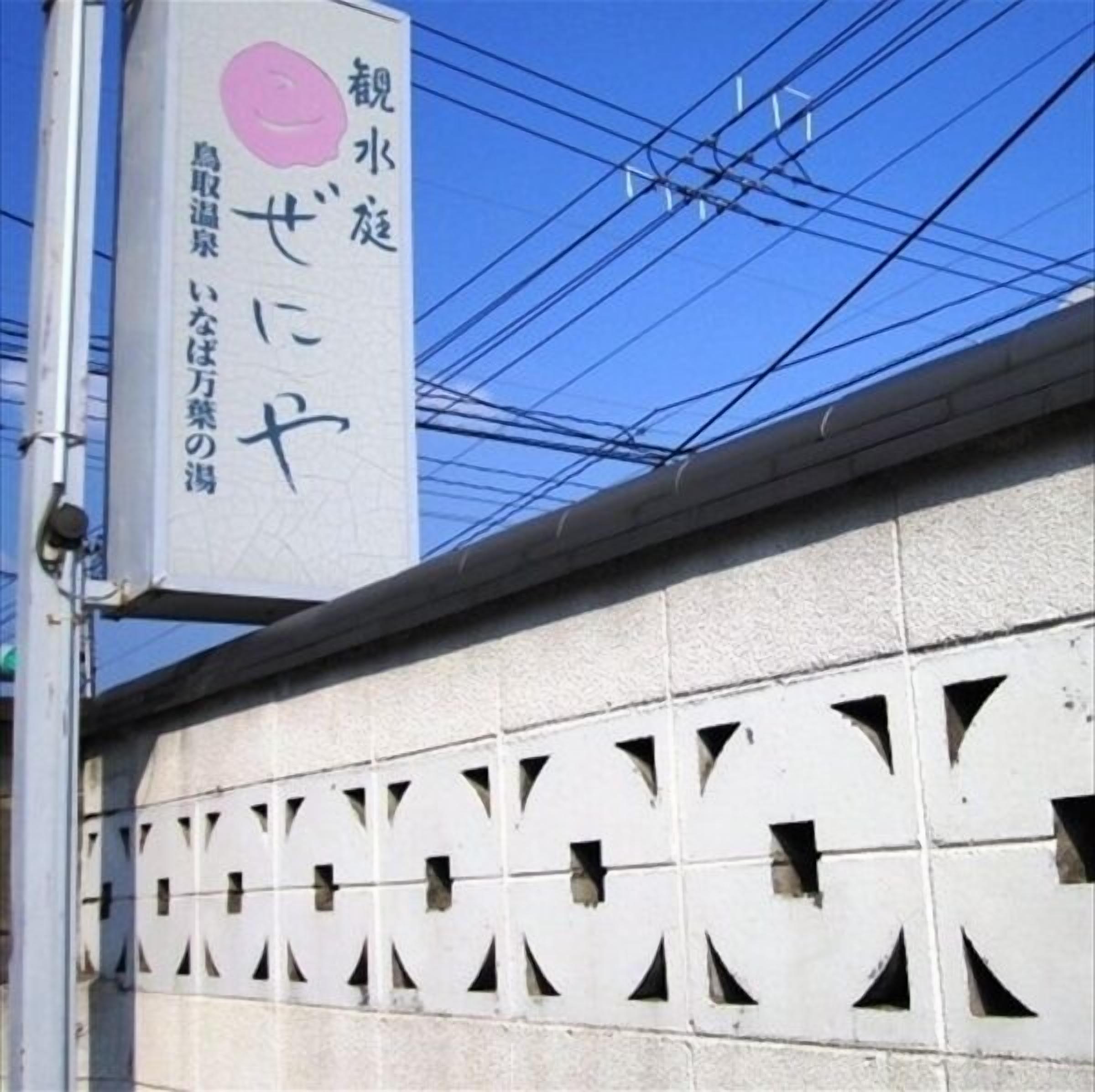 Ein Gebäude mit einer Schilderfassade, die japanische Schriftzeichen und einen rosafarbenen Kreis zeigt.