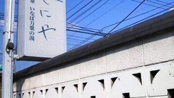Ein Gebäude mit einer Schilderfassade, die japanische Schriftzeichen und einen rosafarbenen Kreis zeigt.