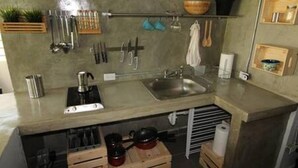 Una cocina con un lavamanos, utensilios y una cafetera.