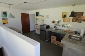 A modern kitchen with a refrigerator, sink, and wooden cabinets.
