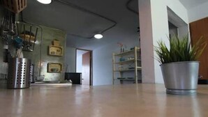 Una habitación amplia con piso de concreto pulido, un estante de metal y una planta en maceta.
