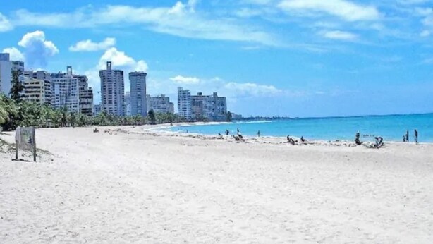 Una playa con edificios al fondo.