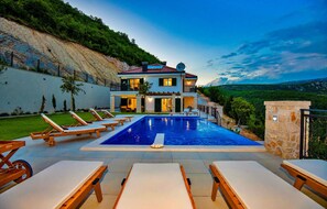 Ein zweistöckiges Haus mit Swimmingpool, Außenbereich und Blick auf die umliegende Landschaft.