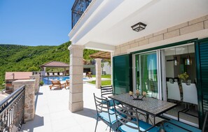 Ein Balkon mit Tisch und Stühlen, im Hintergrund ein Pool und eine Berglandschaft.