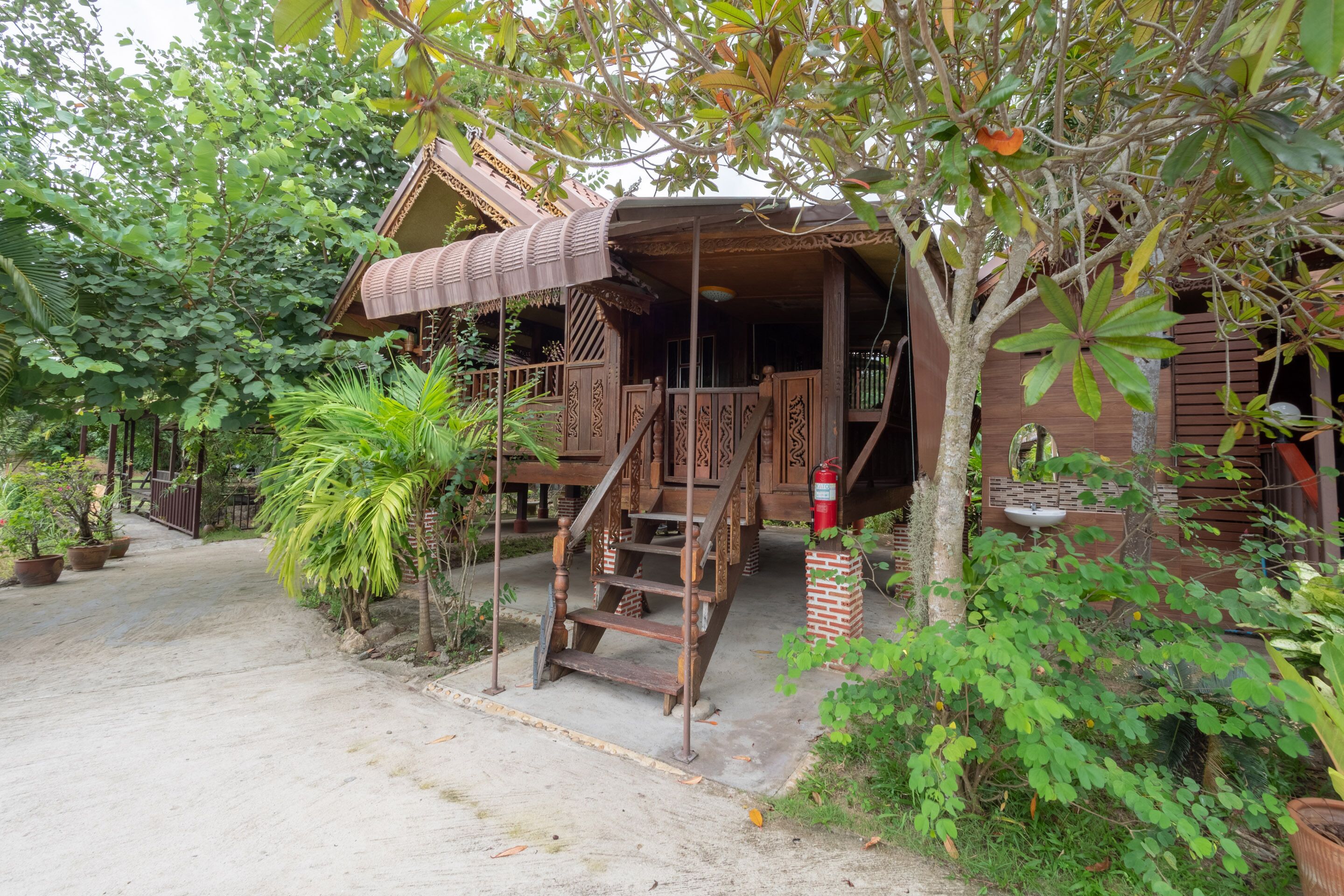 A wooden house with a porch, surrounded by lush greenery.