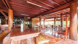 A spacious indoor area with a wooden bar and seating, featuring a herringbone tile floor and exposed wooden beams. - OYO 1128 Ban Suan Meesakul Resort (Sattahip)