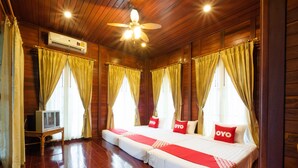 A room with wooden floors, a bed with red and white bedding, a ceiling fan, and curtains. - OYO 1128 Ban Suan Meesakul Resort (Sattahip)