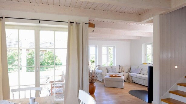 Un vaste espace de vie doté d’un plancher en bois, d’une table à manger avec des chaises, d’un canapé et d’un escalier.